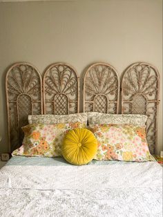 a white bed topped with lots of pillows next to a wall mounted headboard in a bedroom