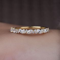 a woman's hand with a yellow gold wedding band that has five diamonds on it