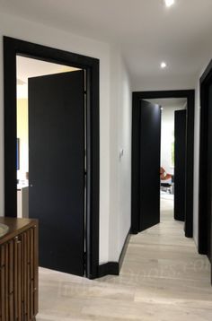 an empty hallway with black doors and white walls