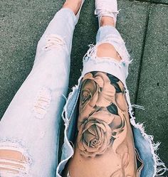 a woman's leg with tattoos on it and ripped up jeans, sitting next to her legs