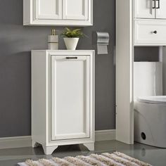 a bathroom with gray walls and white cabinetry, toilet and rug on the floor