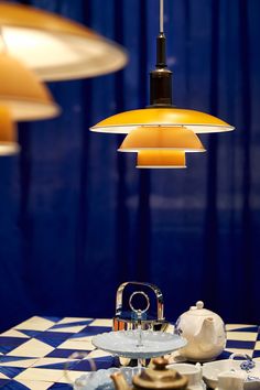 an assortment of teapots, cups and saucers on a checkered table