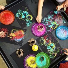 children are making art with paper plates and colored paint on a tray in front of them