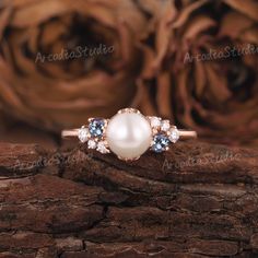 a pearl and diamond ring sitting on top of a piece of wood