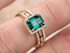 a woman's hand with an emerald and diamond ring