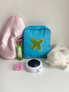 The perfect travel companion and perfect for gifting to anyone with an upcoming trip.  The blue nylon cosmetic case has a airplane patch on the front and a top zipper in gold. Inside the pouch comes a cozy pair of fuzzy socks (pattern may vary slightly), a pink silky cushioned eye mask, pink ear plugs in a clear hard plastic case, a compact hairbrush with mirror and an aloe lip balm.  A must have for any traveler This gift bundle will be shipped beautifully wrapped in cellophane with a gold ribb Blue Travel Pouch Accessories, Portable Blue Travel Pouch, Aloe Lips, Travel Plane, Socks Pattern, Gift Bundle, Hanukkah Gifts, Fuzzy Socks, Sock Patterns