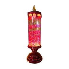 a red candle that is lit up with pink and gold sparkles on it's side