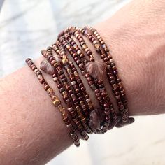 a woman's arm is covered with bracelets and beaded beads, which are stacked on top of each other