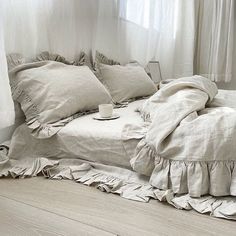 an unmade bed with ruffled linens and a cup of coffee on it