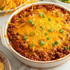 chili cheese and ground beef in a white casserole dish with tortilla chips on the side