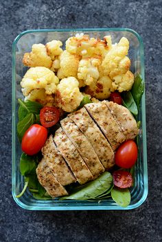 a salad with meat, cauliflower and tomatoes in a glass container on the ground