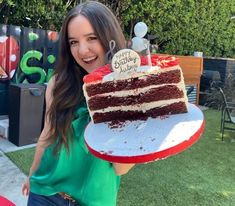 a woman holding up a large piece of cake