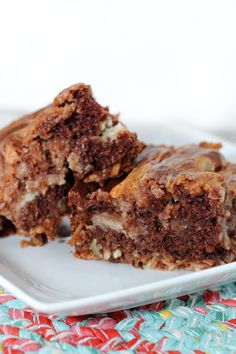 two pieces of brownie on a plate with one bite taken out of the top