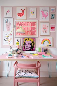 a desk with pink chairs and pictures on the wall above it, along with a lamp