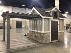 a small building with a roof made out of wood and stone, in a warehouse