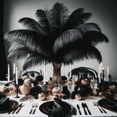 a table set with black and white place settings, palm tree centerpieces and candles