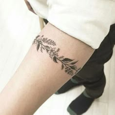 a woman's leg with a tattoo on it that has flowers and leaves growing out of it