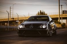 a black car is parked on the side of the road in front of a bridge