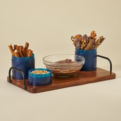 two blue containers filled with food sitting on top of a wooden tray next to a bowl of cereal