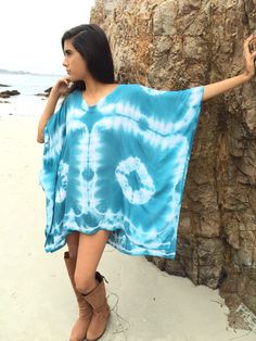 a woman standing on the beach wearing a blue tie - dyed ponchy coverup