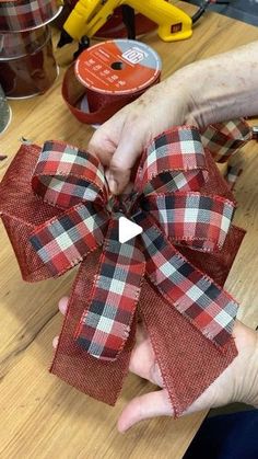 someone is holding a red and black bow on a wooden table with other items in the background