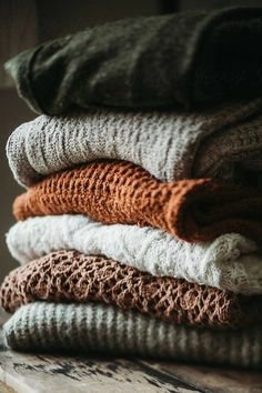 a stack of folded sweaters sitting on top of a wooden table