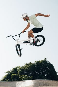 a man flying through the air on top of a white bike with a bicycle attached to it