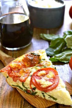 a slice of pizza on a wooden cutting board with tomatoes and basil next to it