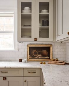 a kitchen with white cabinets and marble counter tops in front of an open cabinet door