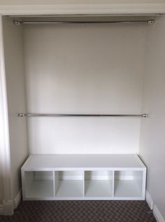 an empty closet with white shelves and metal rails on the wall, in front of a carpeted floor