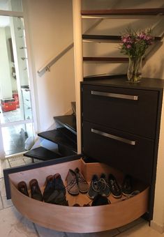 there is a shoe rack with shoes in the bottom drawer and a vase on top