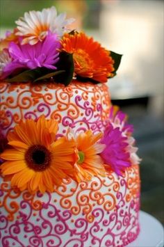 an orange and pink cake with flowers on top