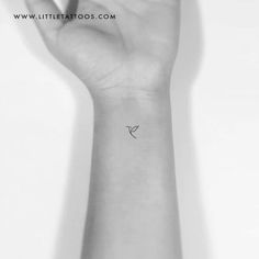 a small tattoo on the wrist of a woman's hand, with a bird flying above it