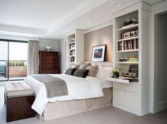 a bedroom with a large bed and lots of books on the shelves next to it