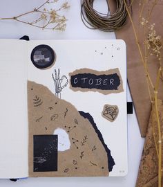 an open notebook sitting on top of a table next to some dried flowers and plants