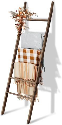 a wooden ladder holding towels and blankets