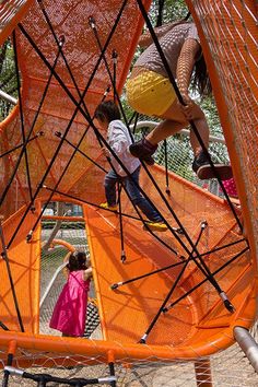 two children playing on an orange playground structure