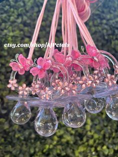 pink flowers are hanging from a chandelier with clear glass beads and pink ribbon