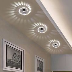 three circular lights are mounted on the ceiling in a room with white walls and flooring