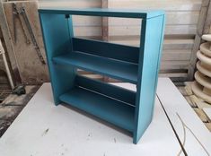 a blue shelf sitting on top of a white table next to stacks of wooden shelves