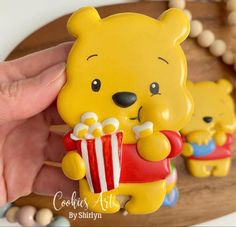 a hand holding a small yellow bear with popcorn