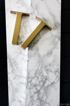 the letter k is made out of marble and gold metal letters are mounted to the wall