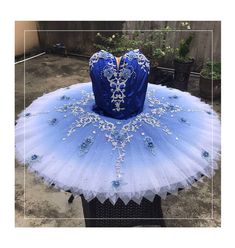 a blue and white tutu is sitting on top of a black table in front of a fence