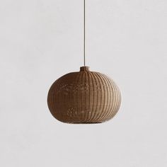 a brown rattan ball hanging from a white wall with a black cord attached to it