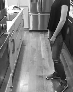 a man standing in the middle of a kitchen with his foot on the counter top