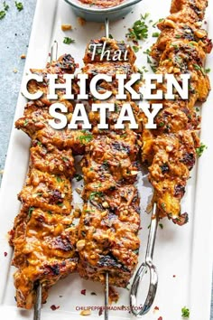 grilled chicken satay on a white platter with dipping sauce