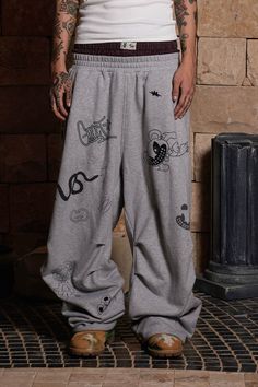 The Graffiti Crinkled Wide-Leg Sweatpants perfectly merge street style with a playful, artistic flair. These sweatpants are adorned with an all-over print of quirky graffiti graphics, adding a vibrant and dynamic touch to the design. The double-waist elastic band provides a unique and comfortable fit, while the crinkled texture along the legs enhances the visual appeal. The back features curved stitching for added dimension, making these pants as stylish as they are comfortable. Crafted from pre Baggy Graphic Print Bottoms For Streetwear, Casual Graphic Print Pants For Streetwear, Baggy Hip Hop Pants With Graphic Print, Baggy Streetwear Pants With Graphic Print, Baggy Graphic Print Pants For Streetwear, Casual Graffiti Print Streetwear Pants, Casual Graffiti Print Pants For Streetwear, Casual Relaxed Fit Pants With Graphic Print, Hip Hop Cotton Bottoms With Graffiti Print