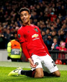 a man sitting on the ground in front of a crowd wearing a red shirt and white shorts