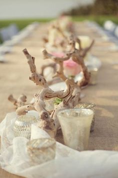 an outdoor table with candles and flowers on it