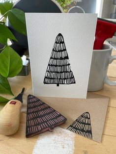 a card with a black and white christmas tree on it next to two pieces of wood